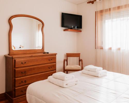 a bedroom with a dresser and a mirror and a bed at La Guardia Apartment in Póvoa de Varzim