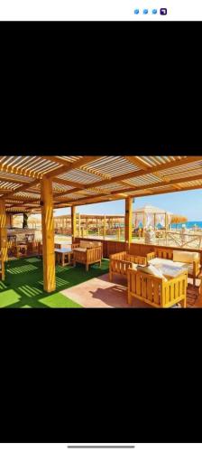 a wooden pavilion with tables and benches under it at Halaشاليه in Ras Sedr