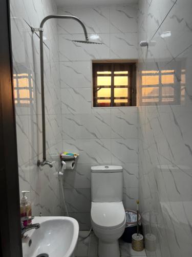 a white bathroom with a toilet and a sink at Private Bedroom with a private bathroom in Bolorunpelu