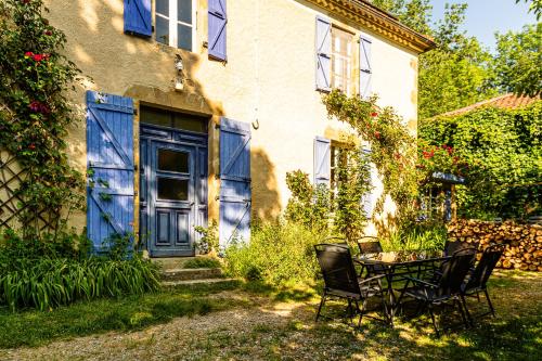 a table and chairs in front of a house with a blue door at Les Portes Neuves! in Belloc-Saint-Clamens