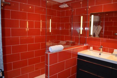 a red tiled bathroom with a sink and a mirror at Hôtel du Bois Blanc Domaine d'Epeyssoles Georges Blanc in Vonnas