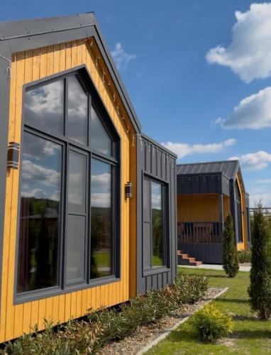 a house with a yellow and black facade at Sosna Park Будиночки in Vynnychky