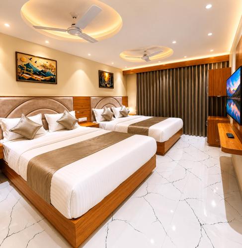 two beds in a hotel room with a flat screen tv at Hotel VAAYU Stay IGI Airport in New Delhi