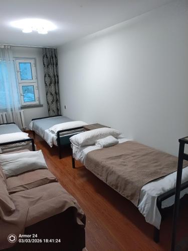 a room with three beds and a window at Tsogoo Guesthouse Shared rooms in Ulaanbaatar