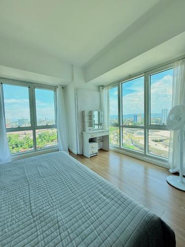 a white bedroom with large windows and a bed with a bed sqor at trendy & Reliable Condo unit in Davao City