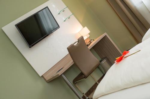 a room with a desk with a television and a chair at Hotel Raffel in Jennersdorf