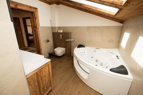 a bathroom with a white tub and a toilet at Frauenalmresort - Chalets in Sankt Lorenzen ob Murau