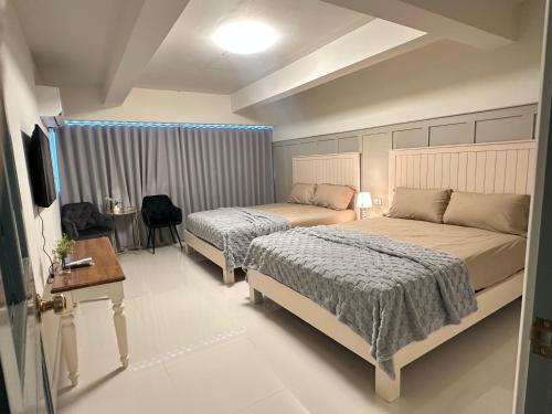a bedroom with two beds and a table and a television at บ้านเคียงคลื่น in Cha Am