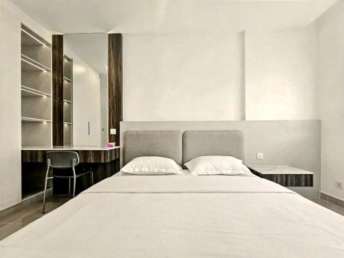 a bedroom with a large white bed and a desk at Modera Suites at Parkland Condo TK in Phnom Penh