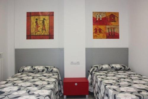two beds in a room with paintings on the wall at Albergue Izar in Viana