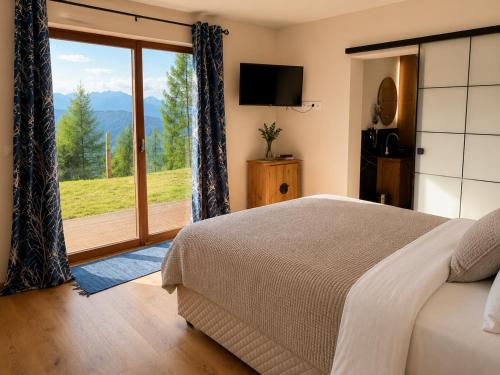 a bedroom with a bed and a sliding glass door at Frauenalmresort - Chalets in Sankt Lorenzen ob Murau