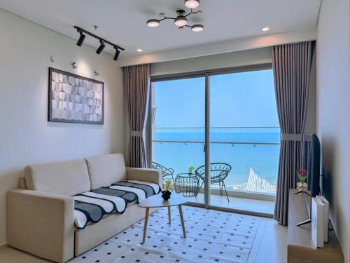 a living room with a couch and a large window at Căn hộ The Song Du lịch biển Tháp Tam Thắng INFINITY POOL FREE IN SIDE THE SEA in Vung Tau