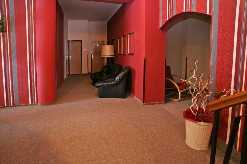 a hallway with red walls and a black leather couch at Hotel Zlaty Jelen in Horažďovice