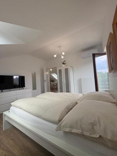 a white bedroom with a large bed and a tv at Apartament Spokojny in Łańcut