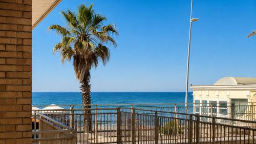 a palm tree on the beach next to the ocean at Oceanine 7 - Seaview Apartment in Lido di Ostia
