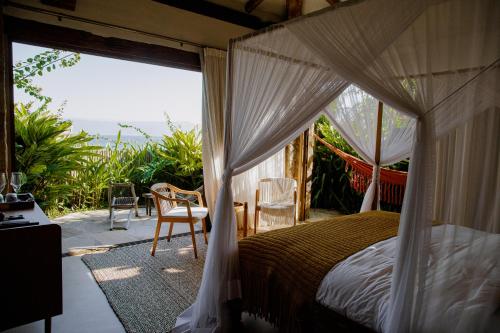 a bedroom with a canopy bed and a balcony at Casa Salga in Ilhabela