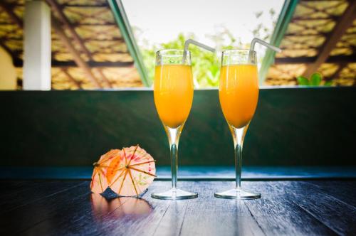 two glasses of orange juice and an umbrella on a table at Garcinia Leaf in Hikkaduwa