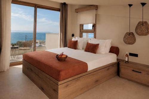 a bedroom with a large bed and a large window at La Brise Luxury Suites in Nea Peramos