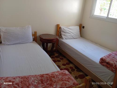 two twin beds in a room with a window at Asrati in Ifrane