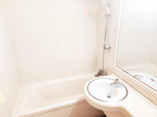 a white bathroom with a sink and a bath tub at 범어사 범어호텔 in Ch'ŏngnyong-dong