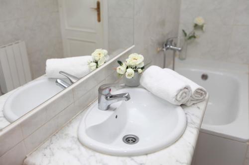 a white bathroom with a sink and a bath tub at Pension La Calma in Barcelona