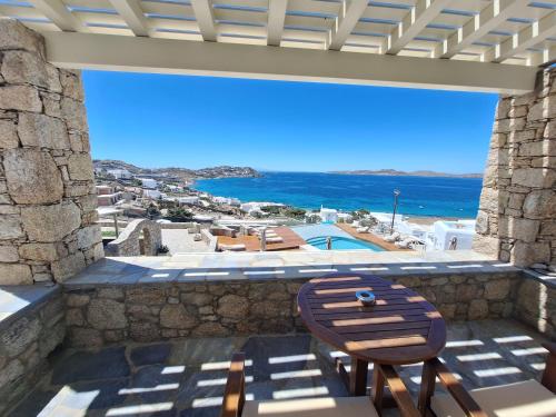 a patio with a wooden bench and a view of the ocean at Panthea Residence in Agios Ioannis Mykonos