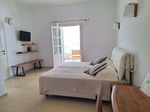 a bedroom with a bed and a table and a window at Panthea Residence in Agios Ioannis Mykonos