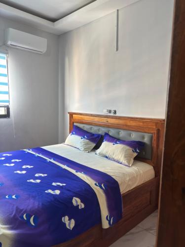a bed with blue and white sheets and pillows at Résidence meublée du boss in Abidjan
