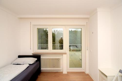 a white room with a bed and a window at Brunnenhof - Serviced Apartments in Bekond