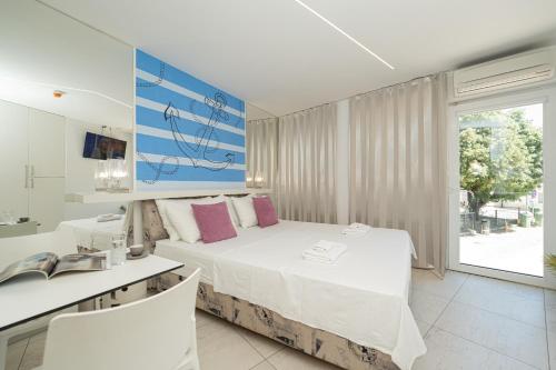 a bedroom with a bed and a desk and a window at Avis Hotel in Novalja