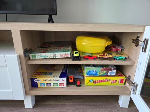 a wooden shelf with toys on it in front of a tv at Comfort flat with great location in Prague