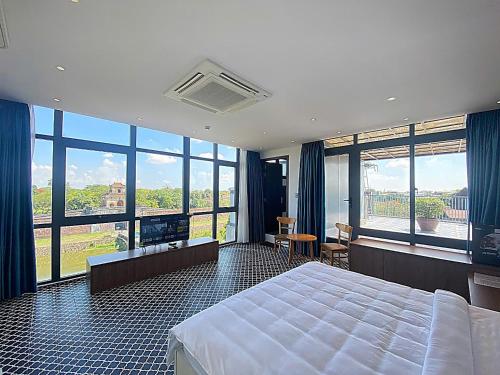 a bedroom with a large bed and large windows at VMona Hotel in Thôn Kim Long (1)