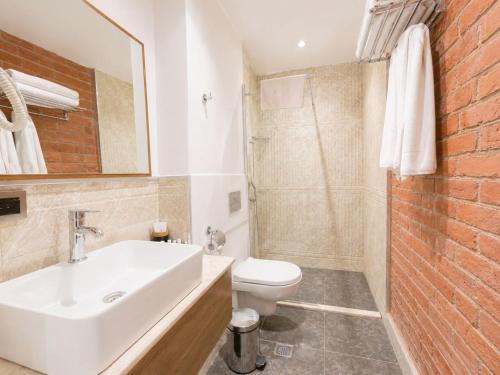 a bathroom with a white sink and a brick wall at LakeSide Hotel & Spa in Gabala