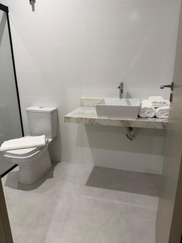 a white bathroom with a toilet and a sink at Studio Liv in Sorriso