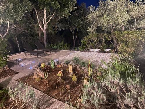 a garden with two chairs and plants and trees at Domo Anghèleda - Detached with large garden in a relaxing environment, a few minutes from the sea in Alghero