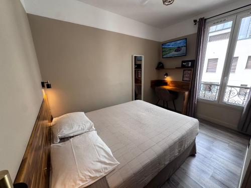 ein Schlafzimmer mit Bett, Schreibtisch und Fenster in der Unterkunft Angleterre Hotel in Paris