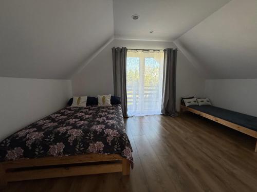 a bedroom with a bed and a large window at Domek Matyjówka in Ustrzyki Dolne