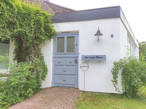 a small white house with a blue door at Dat tweete Tohuus in Soltau