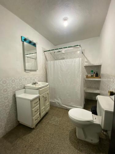 a white bathroom with a toilet and a sink at Los Aposentos Antigua in Antigua Guatemala