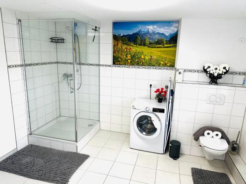 a bathroom with a shower and a washing machine at Bauernhofwohnung Friedrichshafen in Friedrichshafen