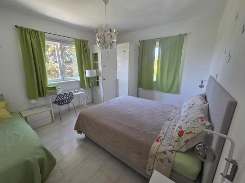 a bedroom with green curtains and a bed and a table at Apartment Mia in Rab