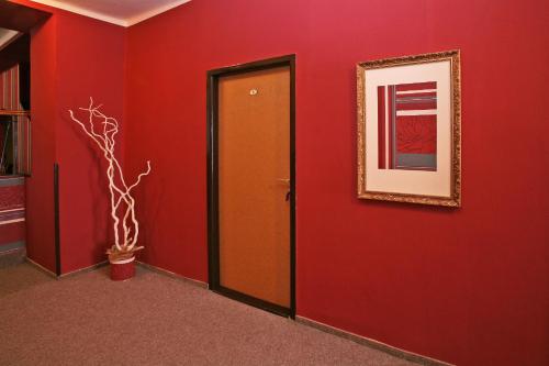a hallway with red walls and a door and a picture at Hotel Zlaty Jelen in Horažďovice