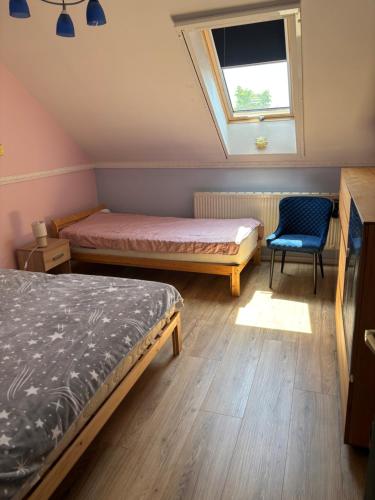 a bedroom with two beds and a window and a chair at Vidéki Vendégház in Doboz
