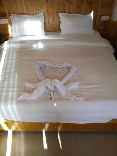 a white bed with a towel in the shape of a heart at The Snow Rock in Palchān