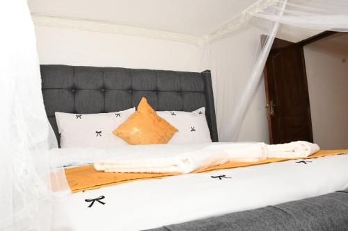 a bed with a black headboard and white pillows at Progressive Success Residency in Juja