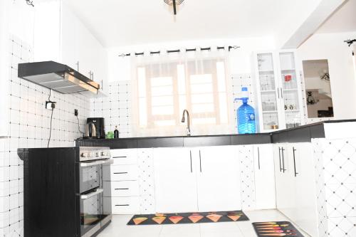 a kitchen with white walls and a black counter top at Progressive Success Residency in Juja