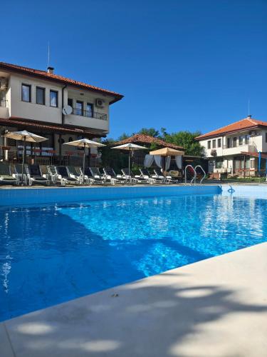 a blue swimming pool with chairs and umbrellas at Бадевски рай-къща Любов in Badewzi