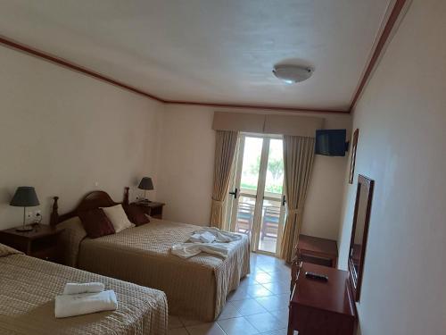 a hotel room with two beds and a window at Porto Fico Hotel in Vasiliki