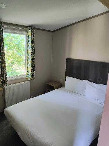 a bedroom with a large white bed and a window at Rosie Caravan Selsey in Selsey