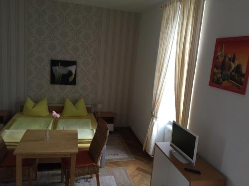 - une chambre avec un lit, une table et une télévision dans l'établissement Pension Gutshaus, à Halle-sur-Saale